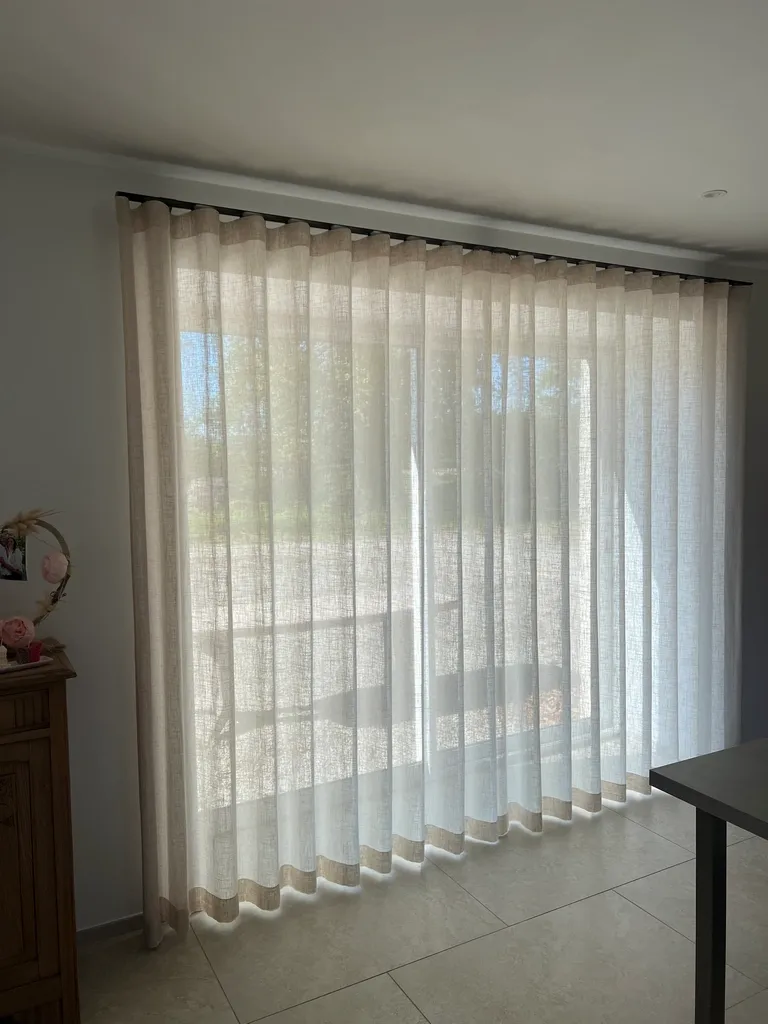 Voilages en lin sur baie coulissante dans un séjour avec mobilier en bois